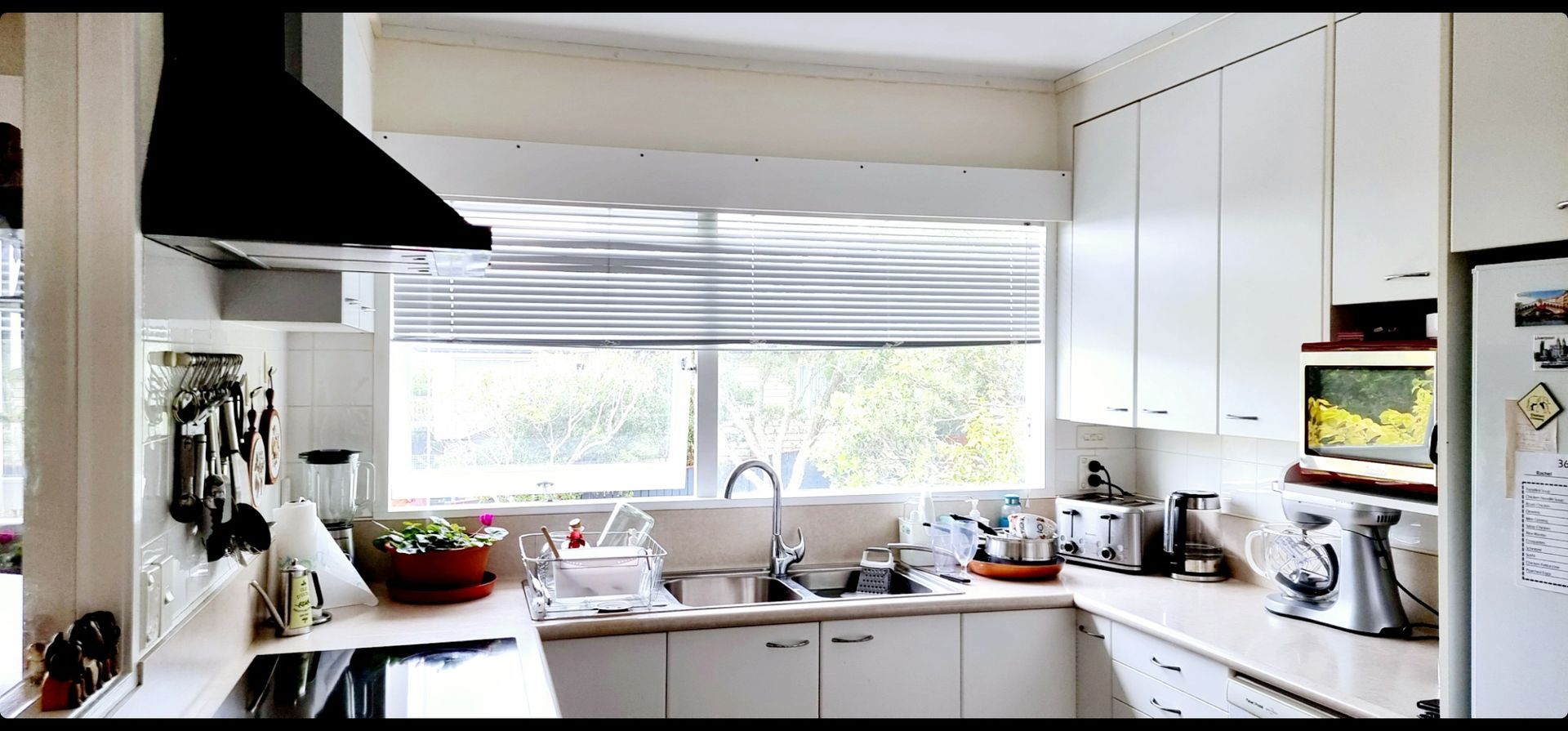 A kitchen with white cabinets and a black hood