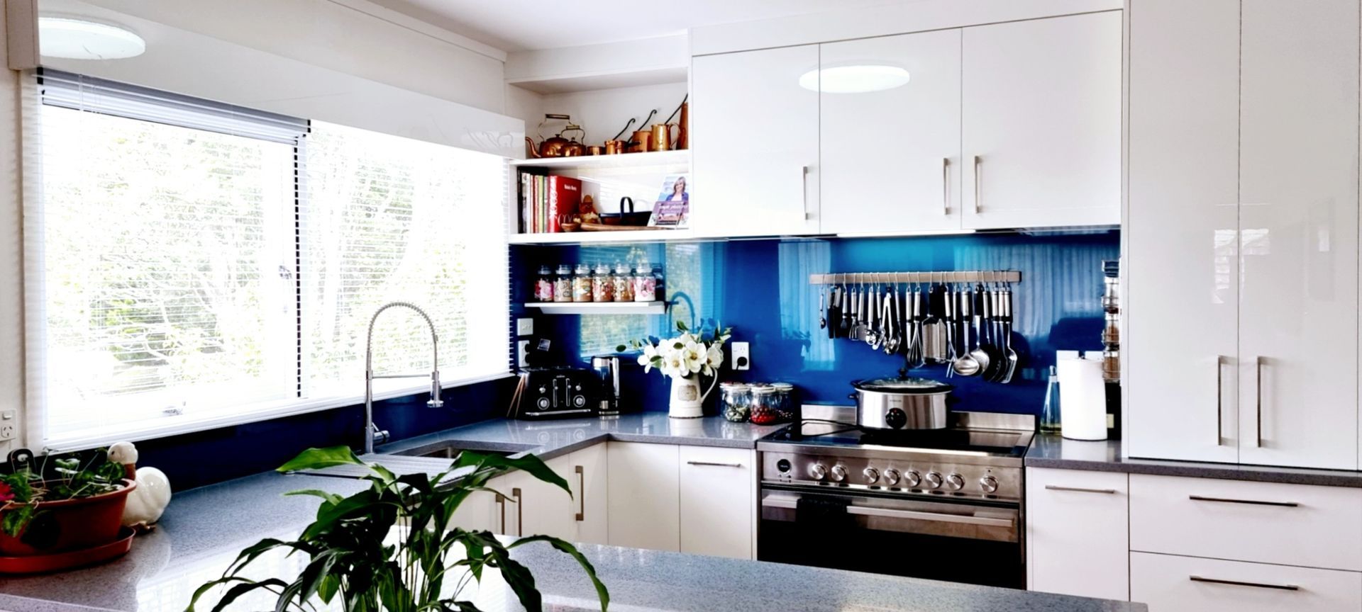 A kitchen with white cabinets and a blue backsplash