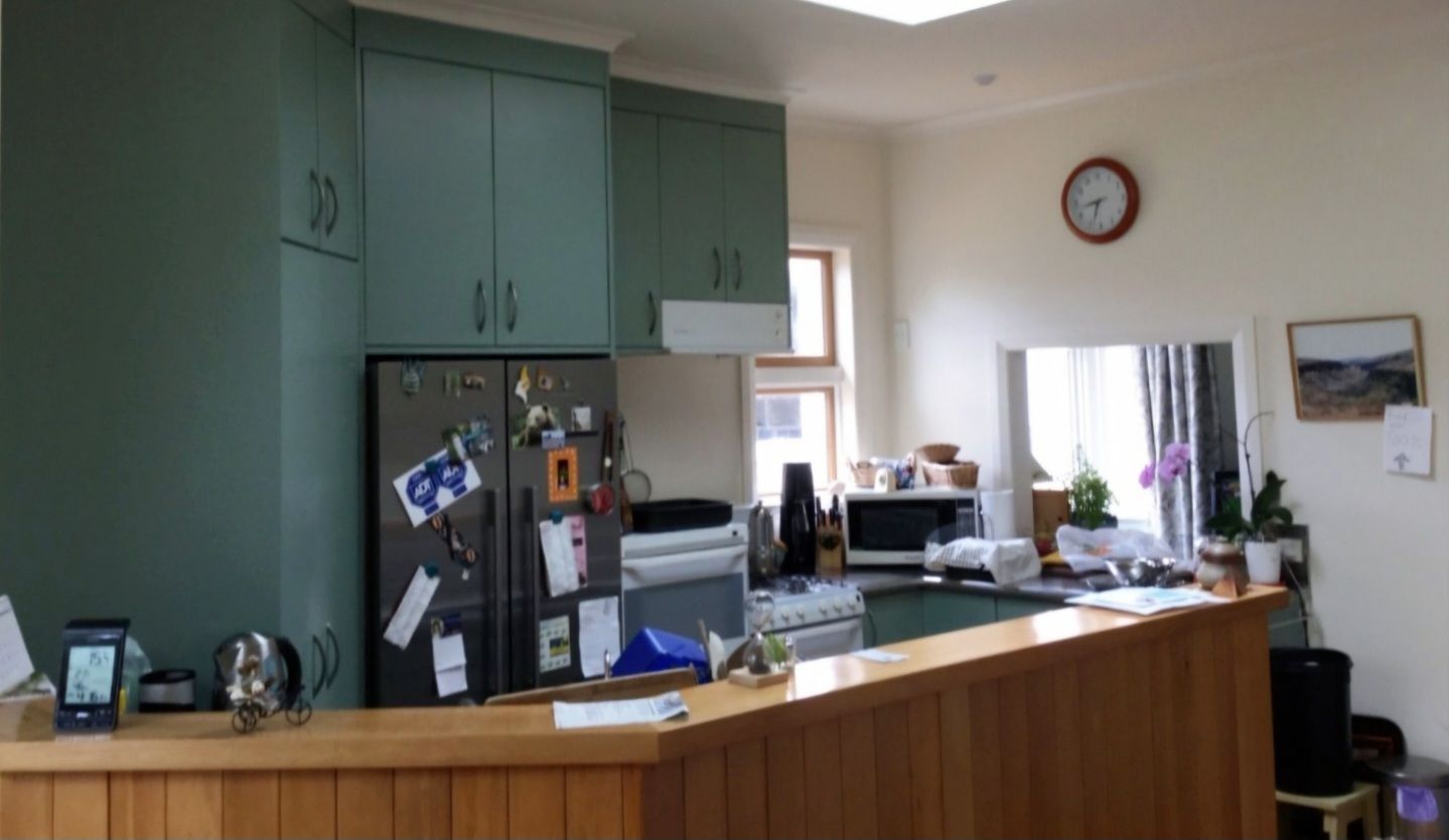 A kitchen with green cabinets and a clock on the wall