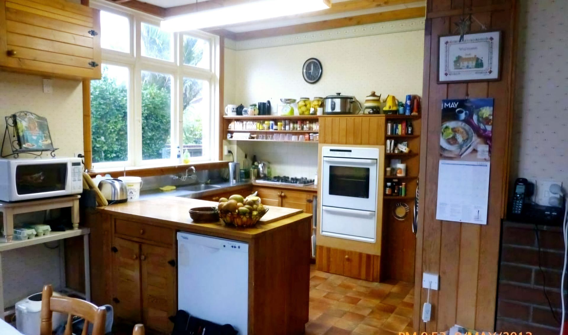 A kitchen with wooden cabinets and a calendar on the wall