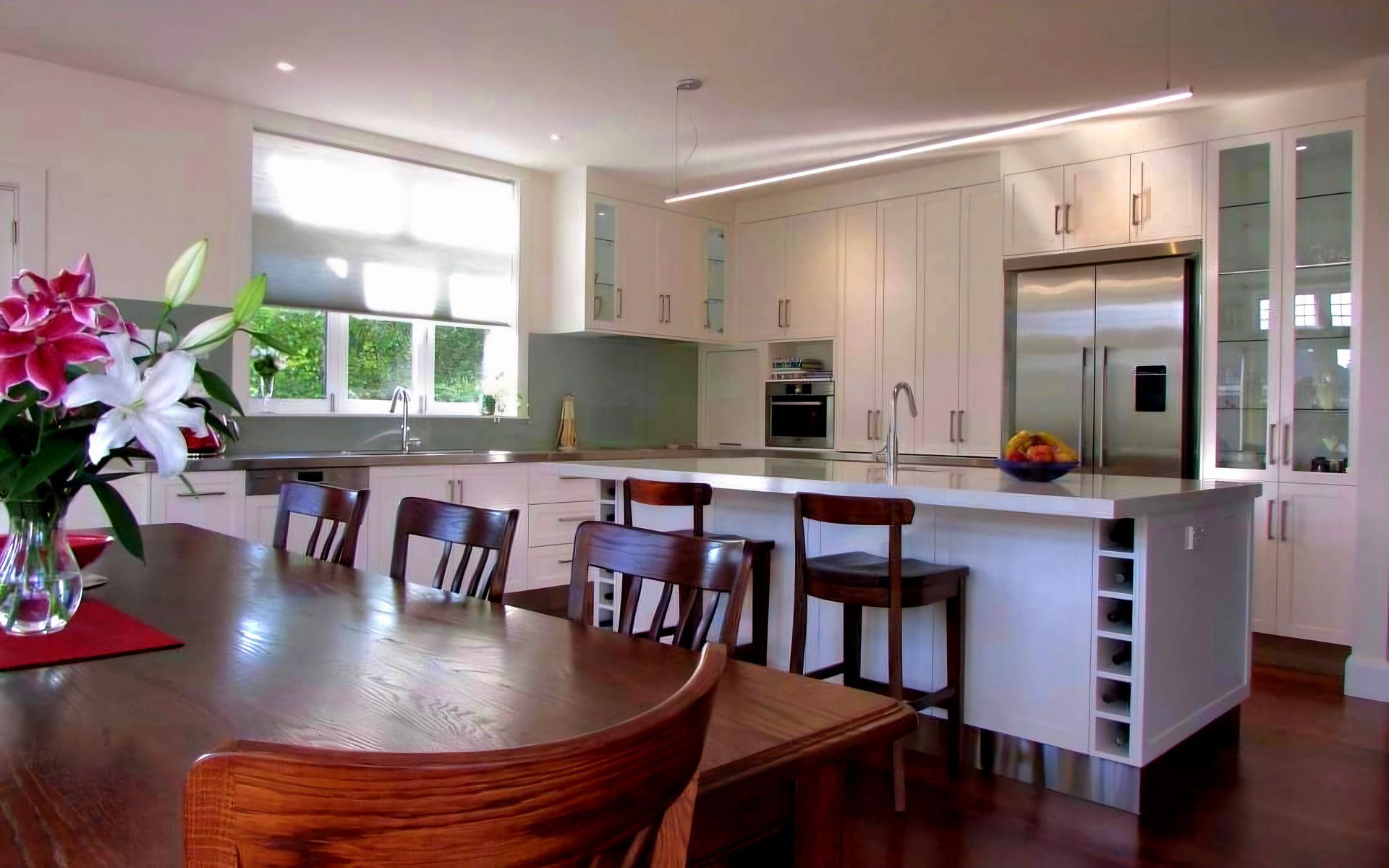 A kitchen with a table and chairs and a vase of flowers on the table.