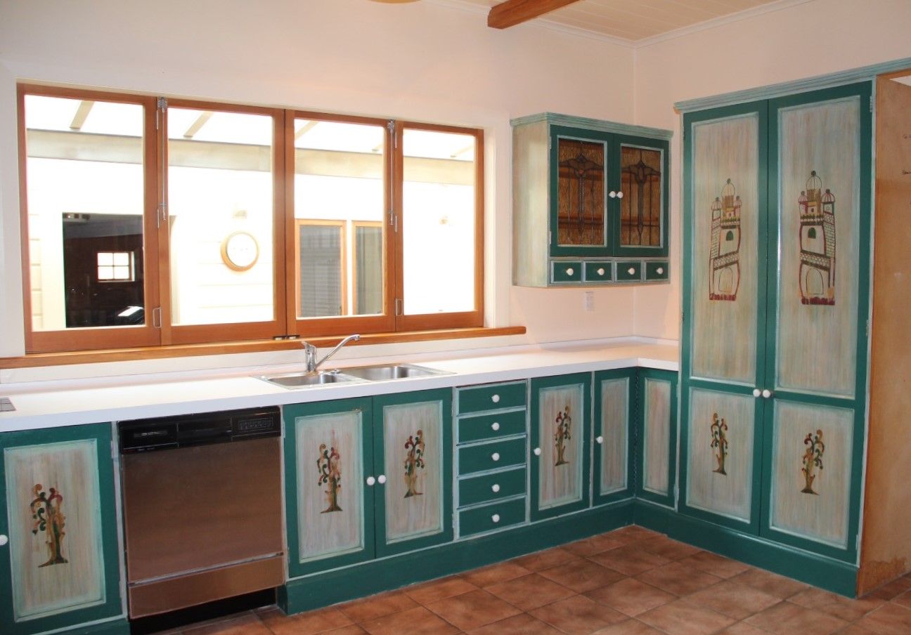 A kitchen with green cabinets and white counter tops