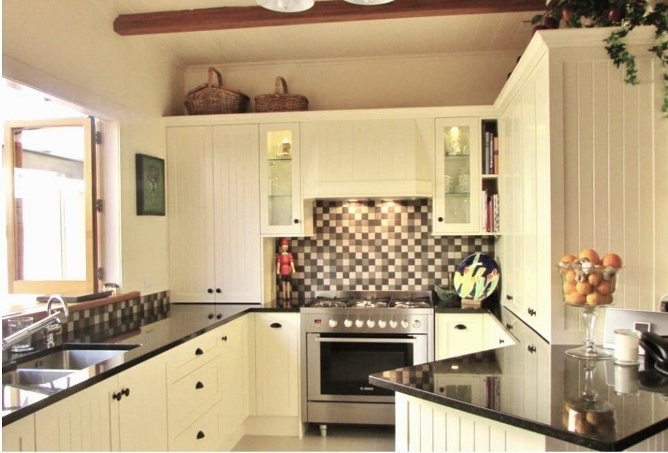 A kitchen with white cabinets and black counter tops