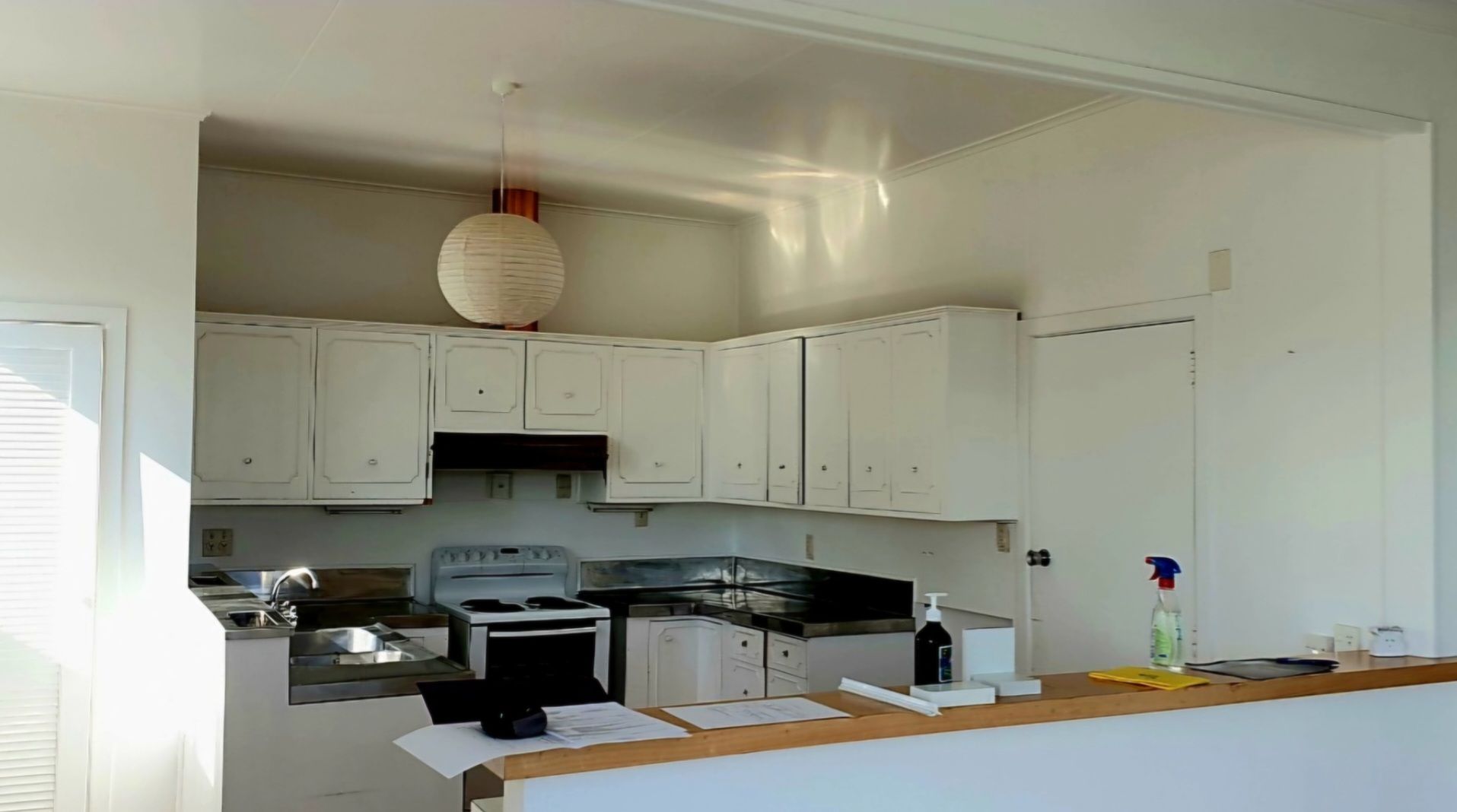 An empty kitchen with white cabinets and a stove.