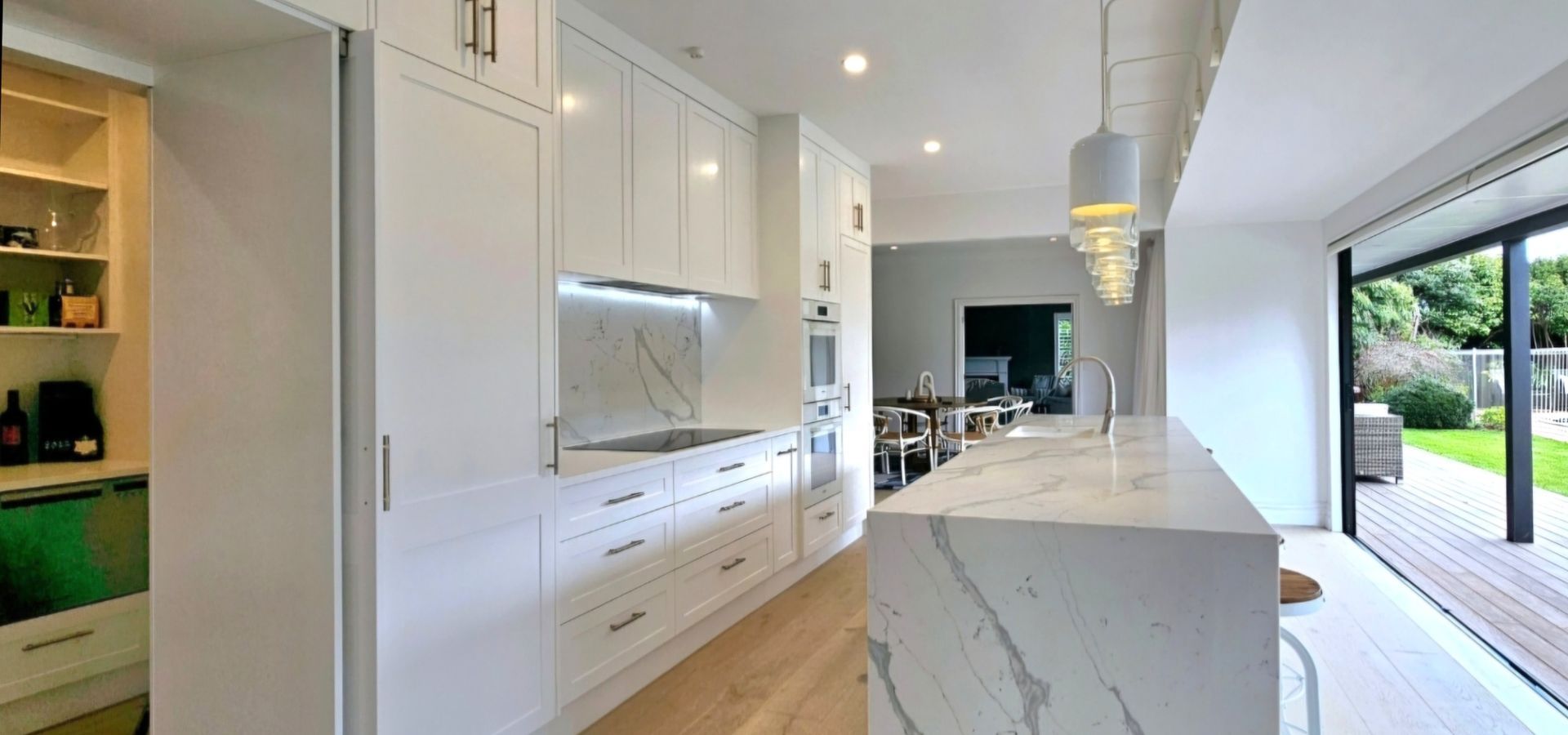 A kitchen with white cabinets and a marble counter top.