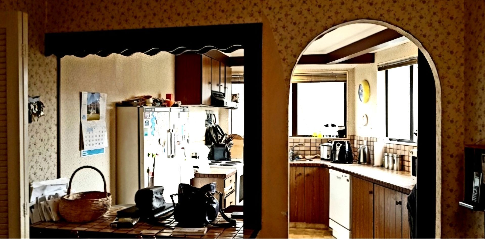 A kitchen with an archway between the kitchen and the living room