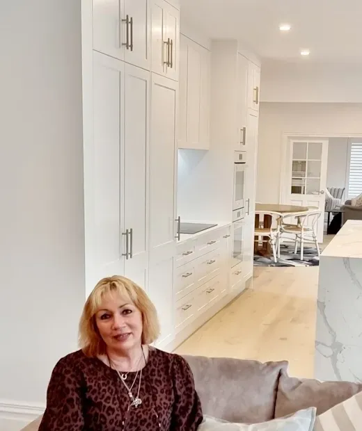 A woman is sitting on a couch in a kitchen