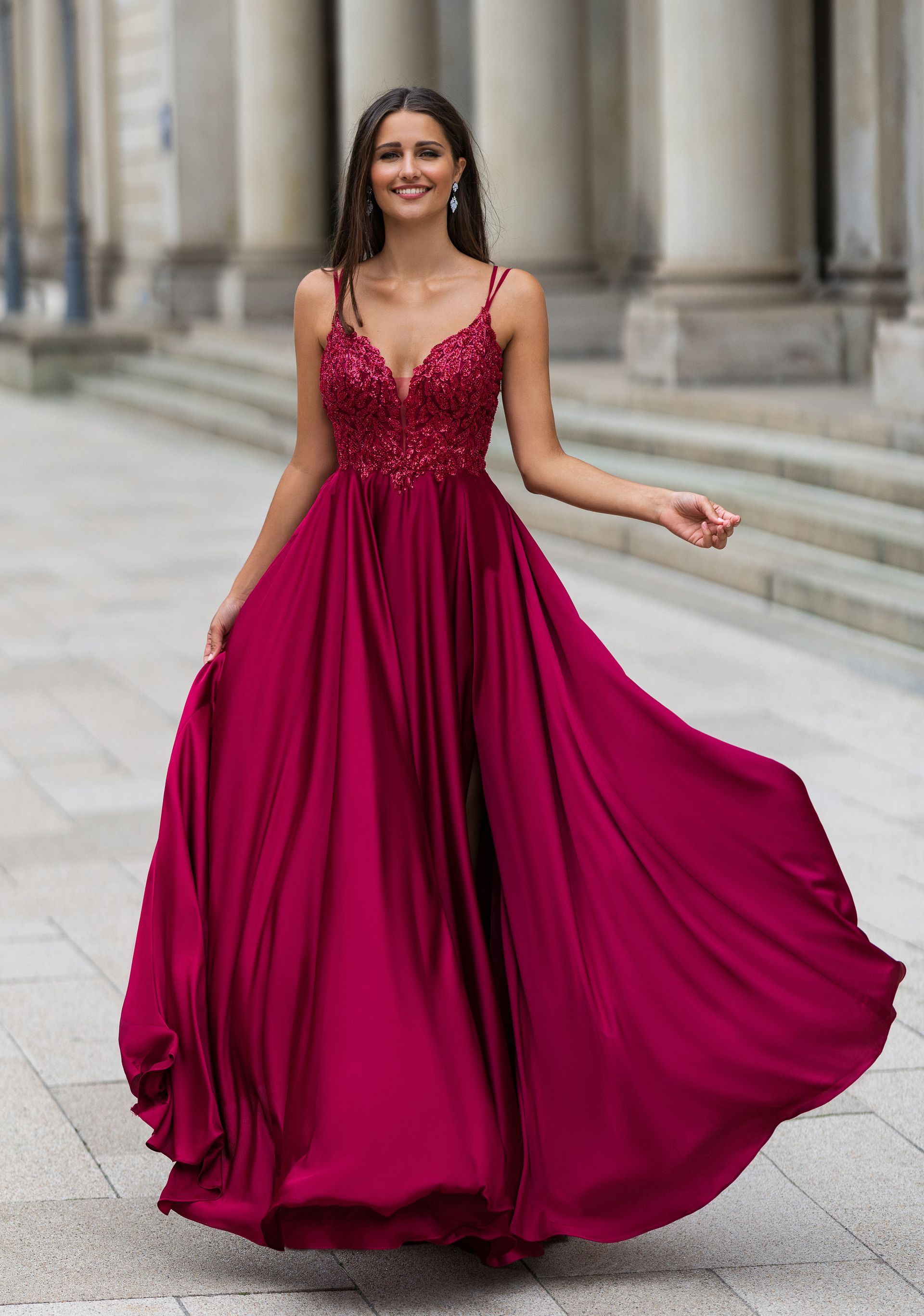 Eine Frau in einem langen roten Kleid steht vor einem Gebäude.