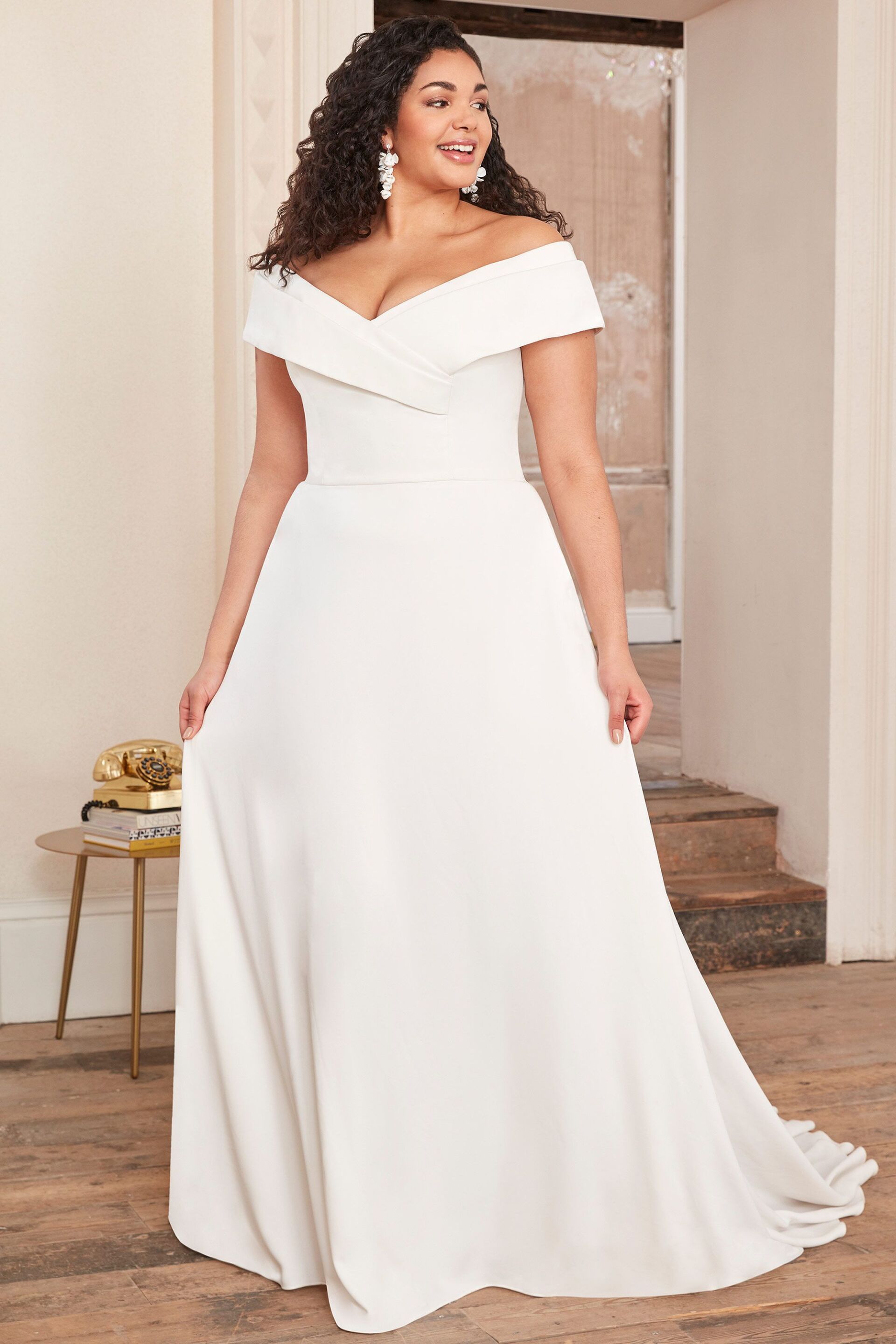 Eine Frau mit Übergröße trägt ein schulterfreies, weißes Brautkleid.