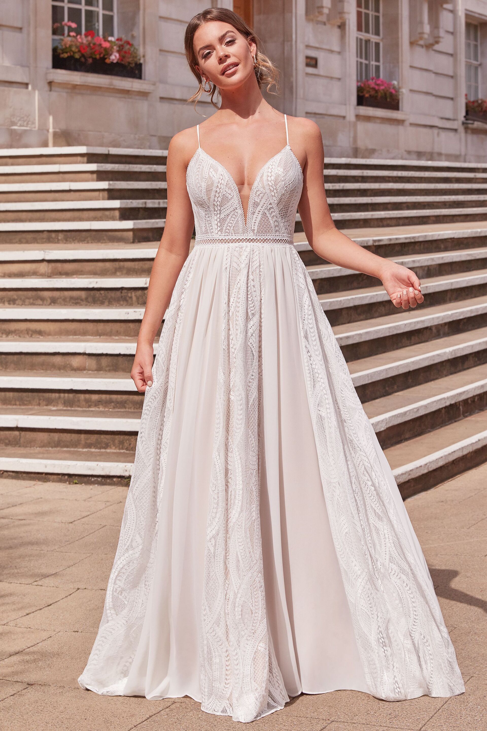 Eine Frau in einem weißen Brautkleid steht auf einer Treppe.