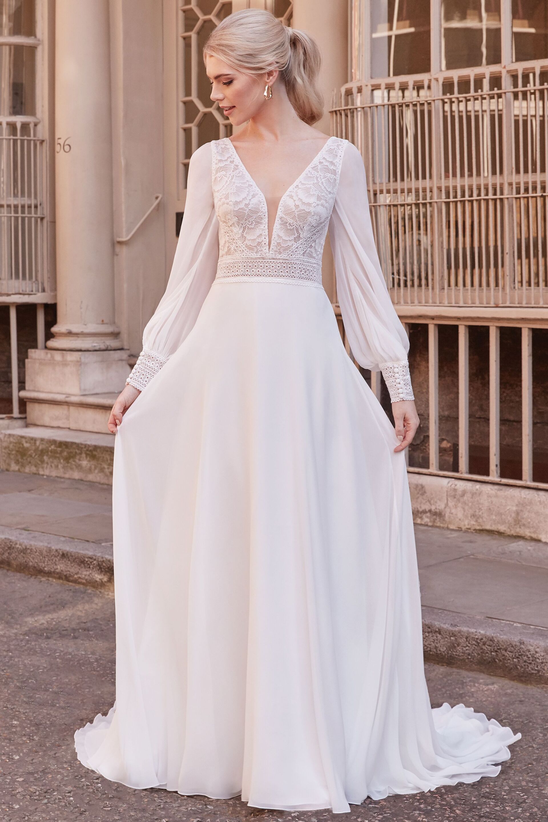 Eine Frau trägt ein weißes Hochzeitskleid mit langen Ärmeln.