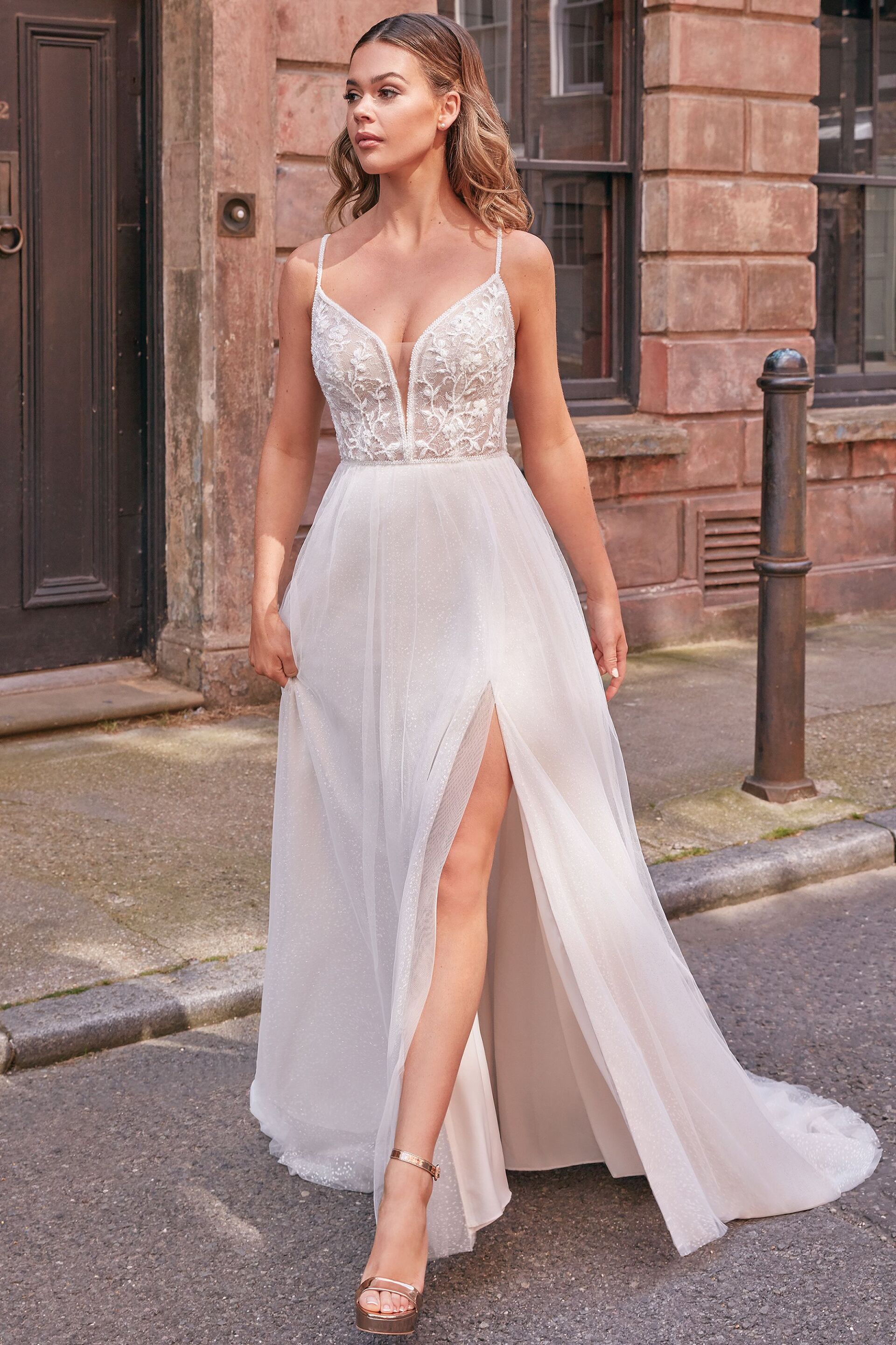 Eine Frau trägt ein weißes Brautkleid mit hohem Schlitz.