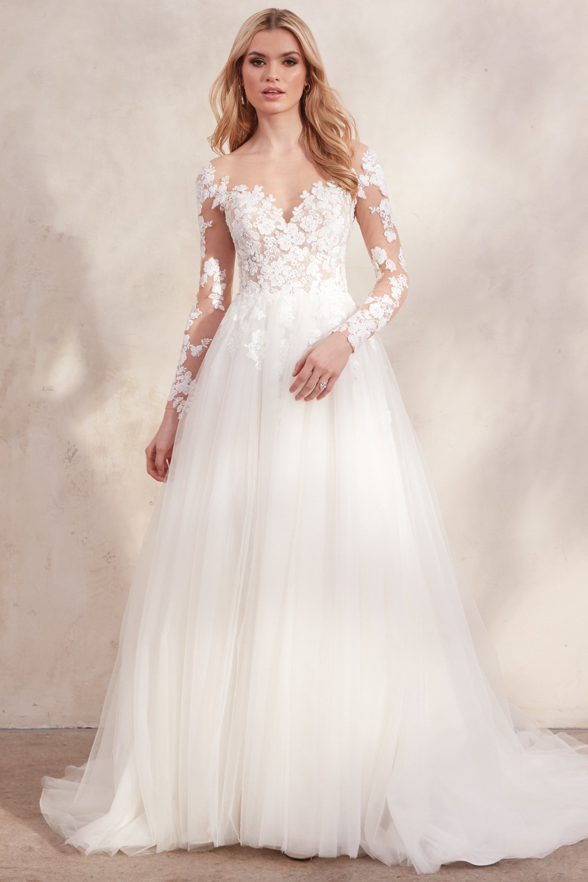 Eine Frau trägt ein weißes Hochzeitskleid mit langen Ärmeln.