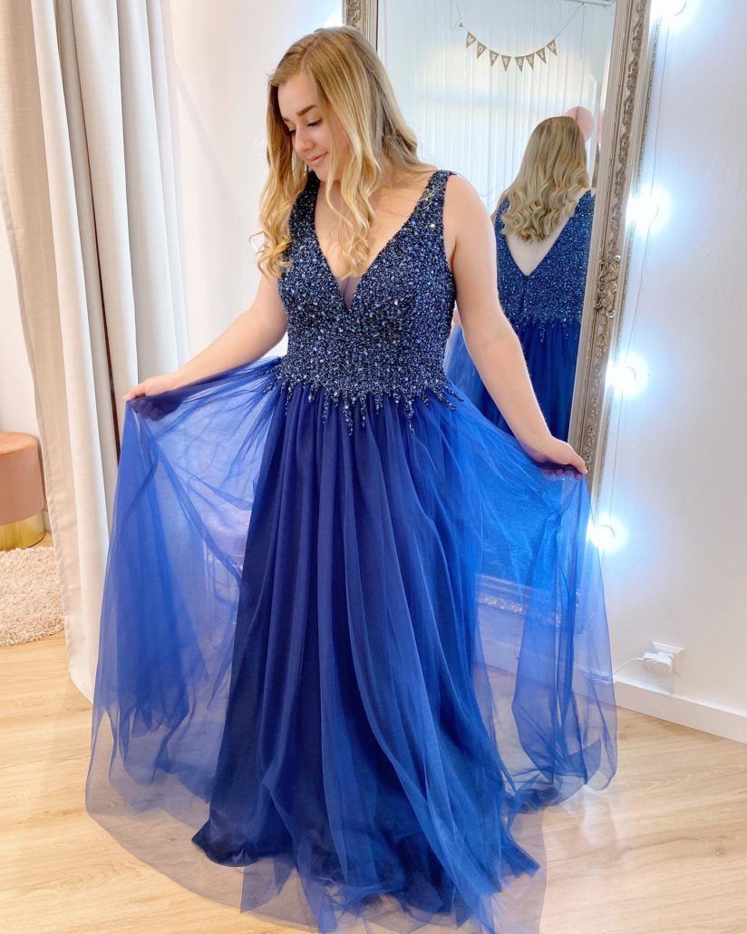 Eine Frau in einem blauen Kleid steht vor einem Spiegel.