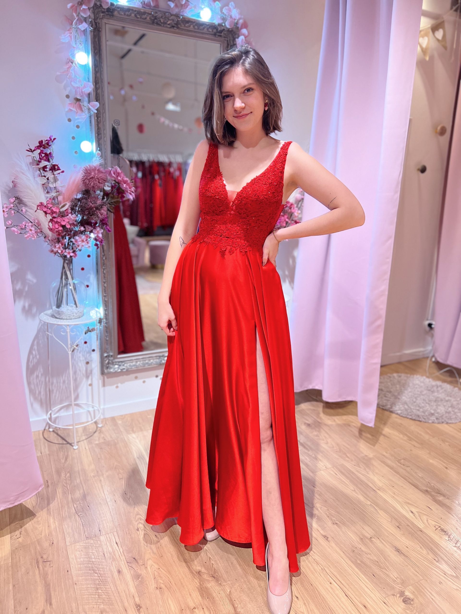 Eine Frau in einem roten Kleid steht vor einem Spiegel.