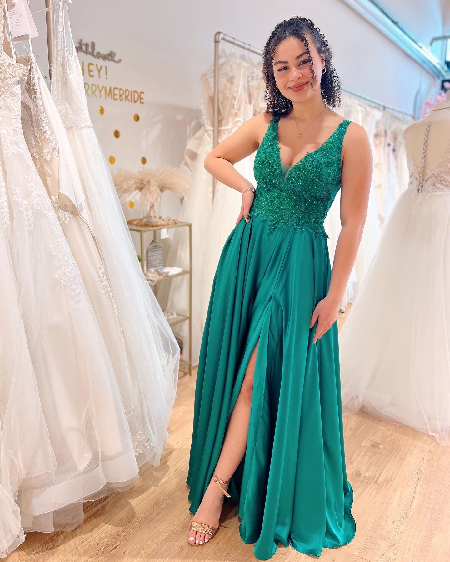 Eine Frau in einem grünen Kleid steht in einem Brautmodengeschäft.
