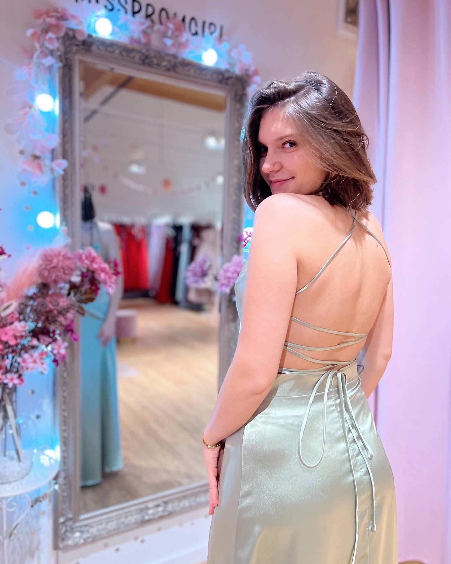 Eine Frau in einem grünen Kleid steht vor einem Spiegel.