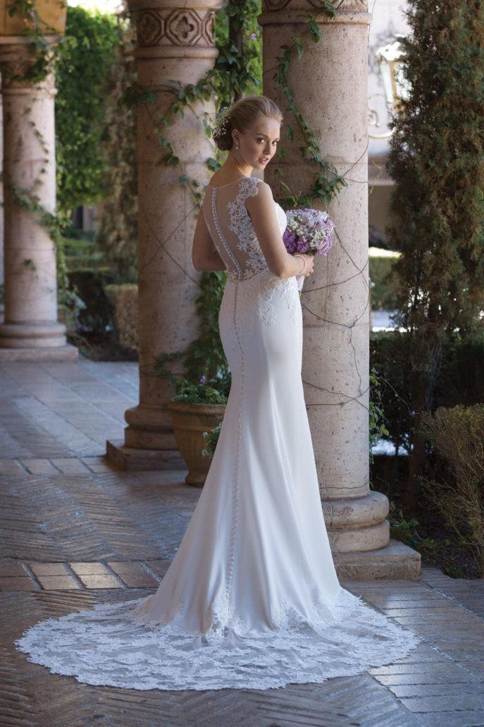 Eine Frau trägt ein Brautkleid und hält einen Blumenstrauß.