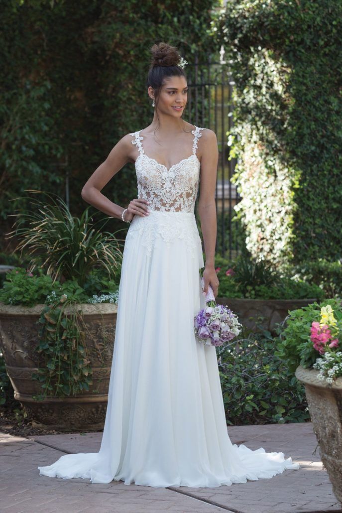 Eine Frau in einem weißen Hochzeitskleid hält einen Blumenstrauß.