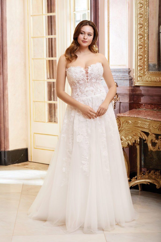 Eine Frau in einem weißen Brautkleid steht in einem Raum.