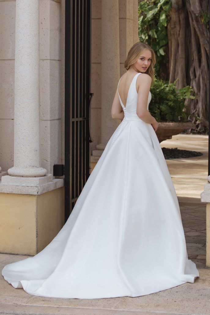 Eine Frau in einem weißen Brautkleid steht vor einem Gebäude.