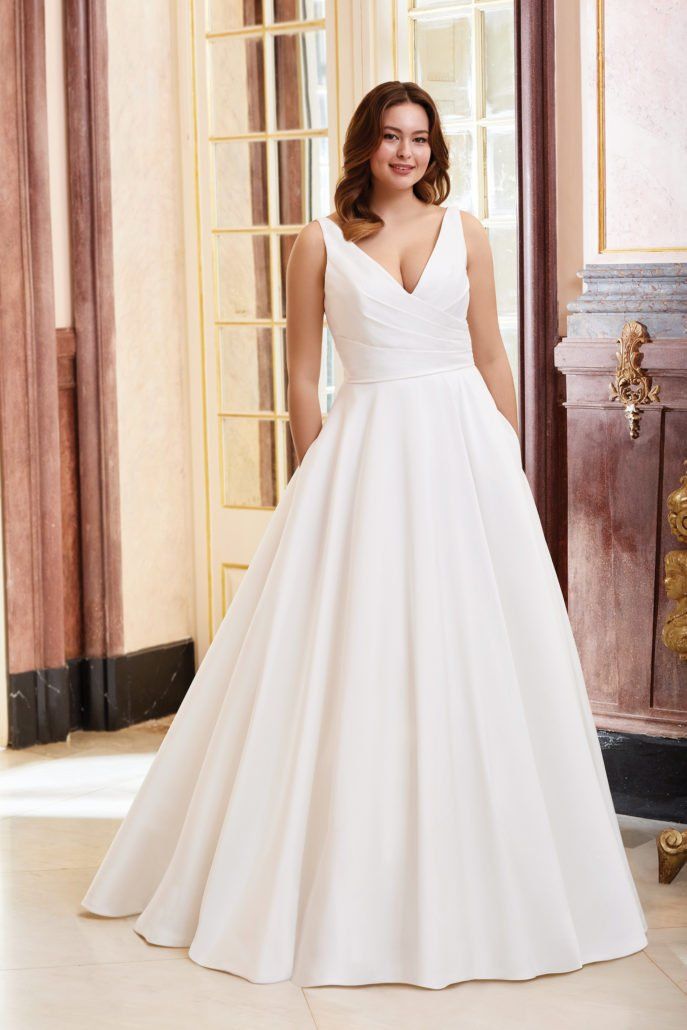 Eine Frau in einem weißen Brautkleid steht in einem Raum.