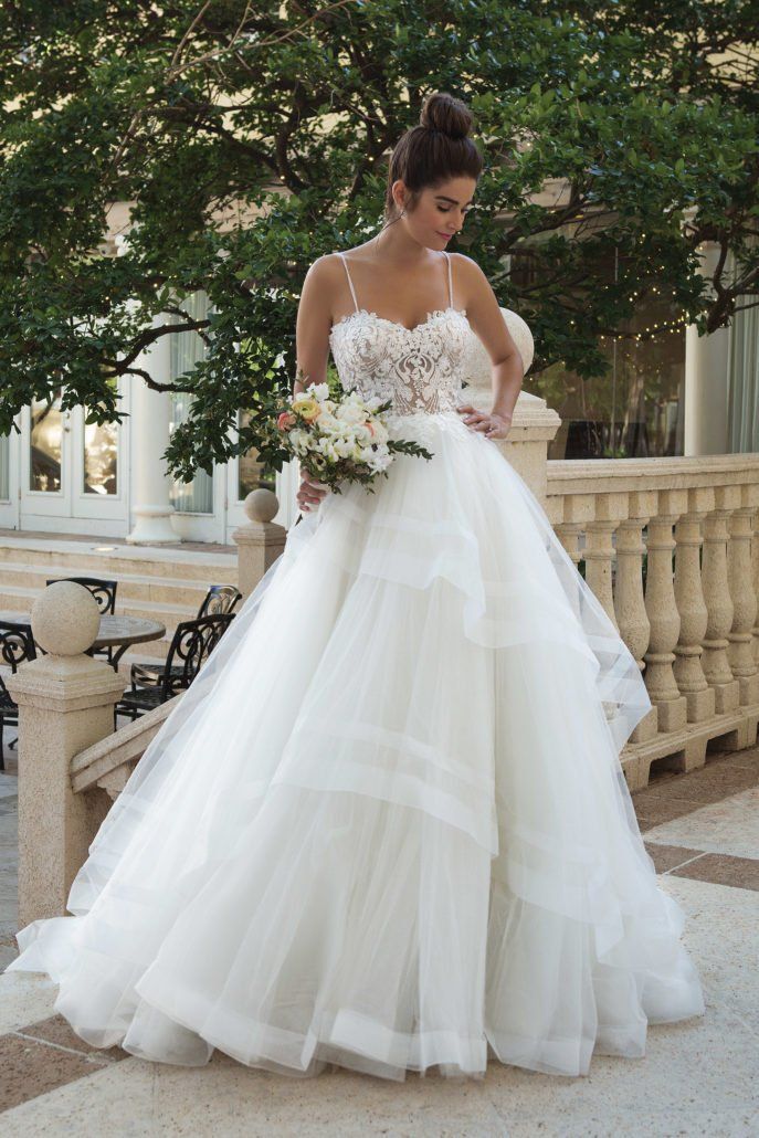 Eine Frau in einem weißen Hochzeitskleid hält einen Blumenstrauß.