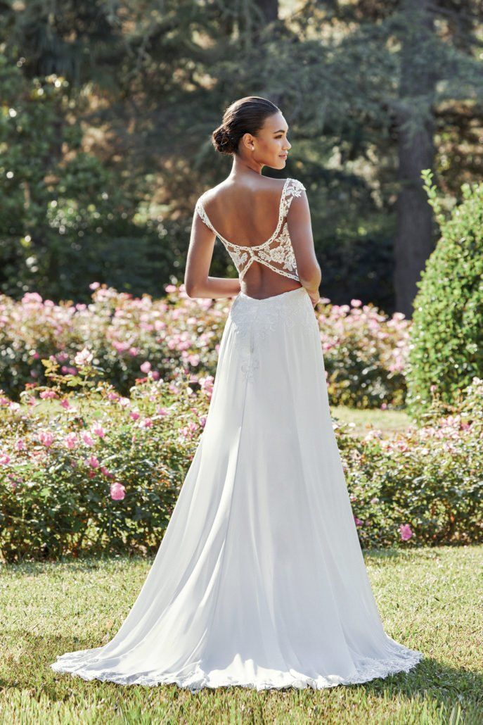Eine Frau in einem Hochzeitskleid steht in einem Blumenfeld.