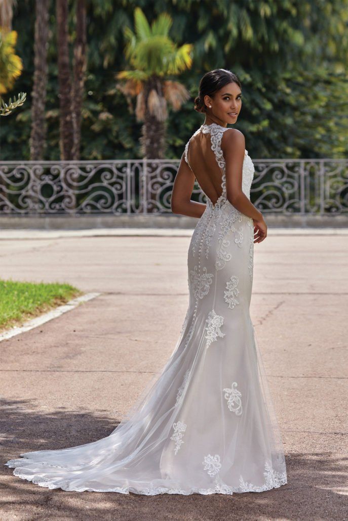 Eine Frau in einem Brautkleid steht vor einem Zaun.