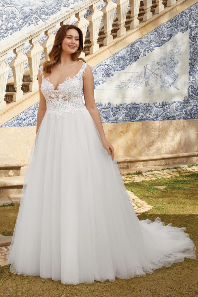 Eine Frau in einem weißen Brautkleid steht vor einer Treppe.