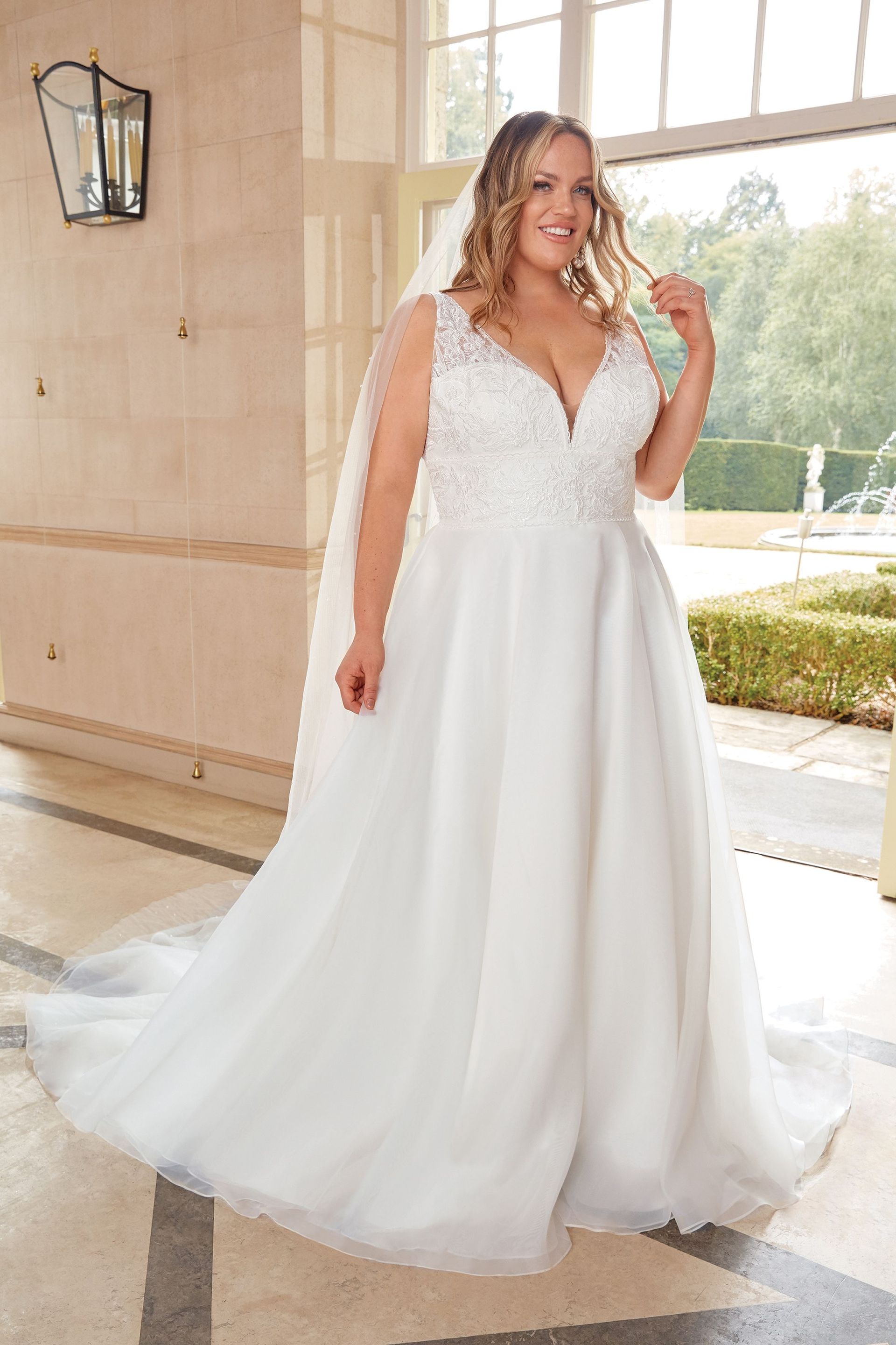 Eine Übergrößenfrau trägt ein weißes Hochzeitskleid und einen Schleier.