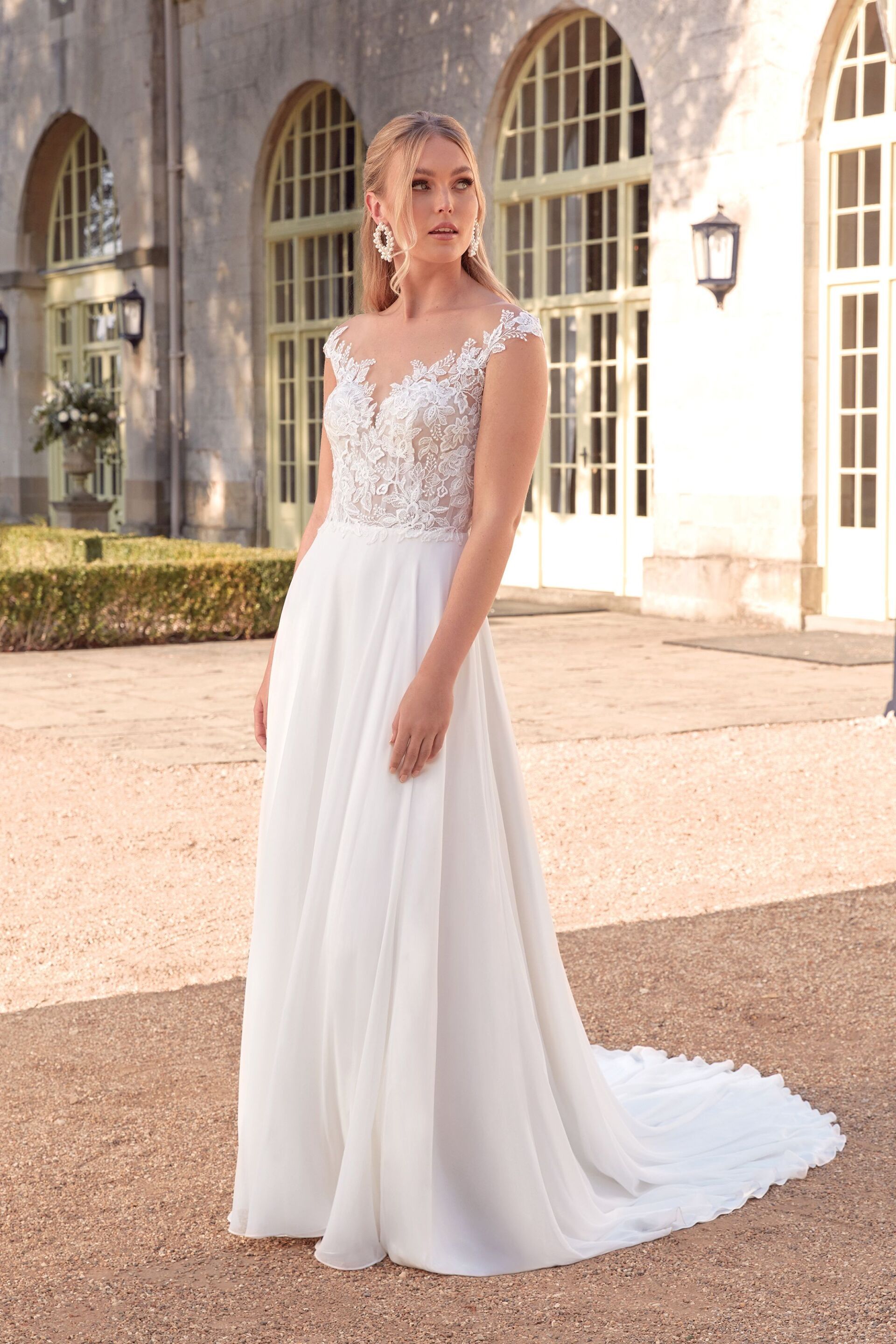 Eine Frau in einem weißen Brautkleid steht vor einem Gebäude.