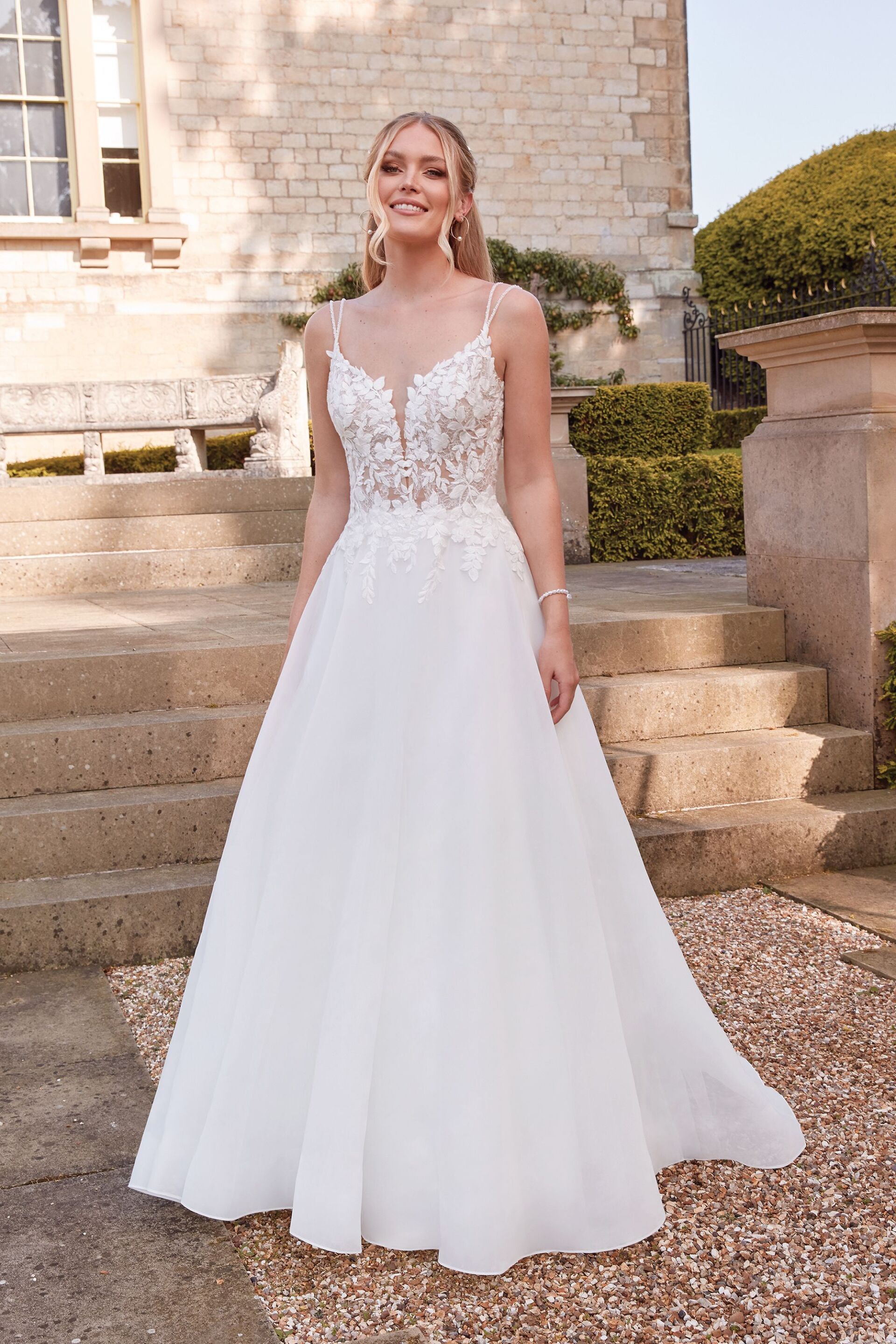 Eine Frau trägt ein weißes Hochzeitskleid und steht auf einer Treppe.