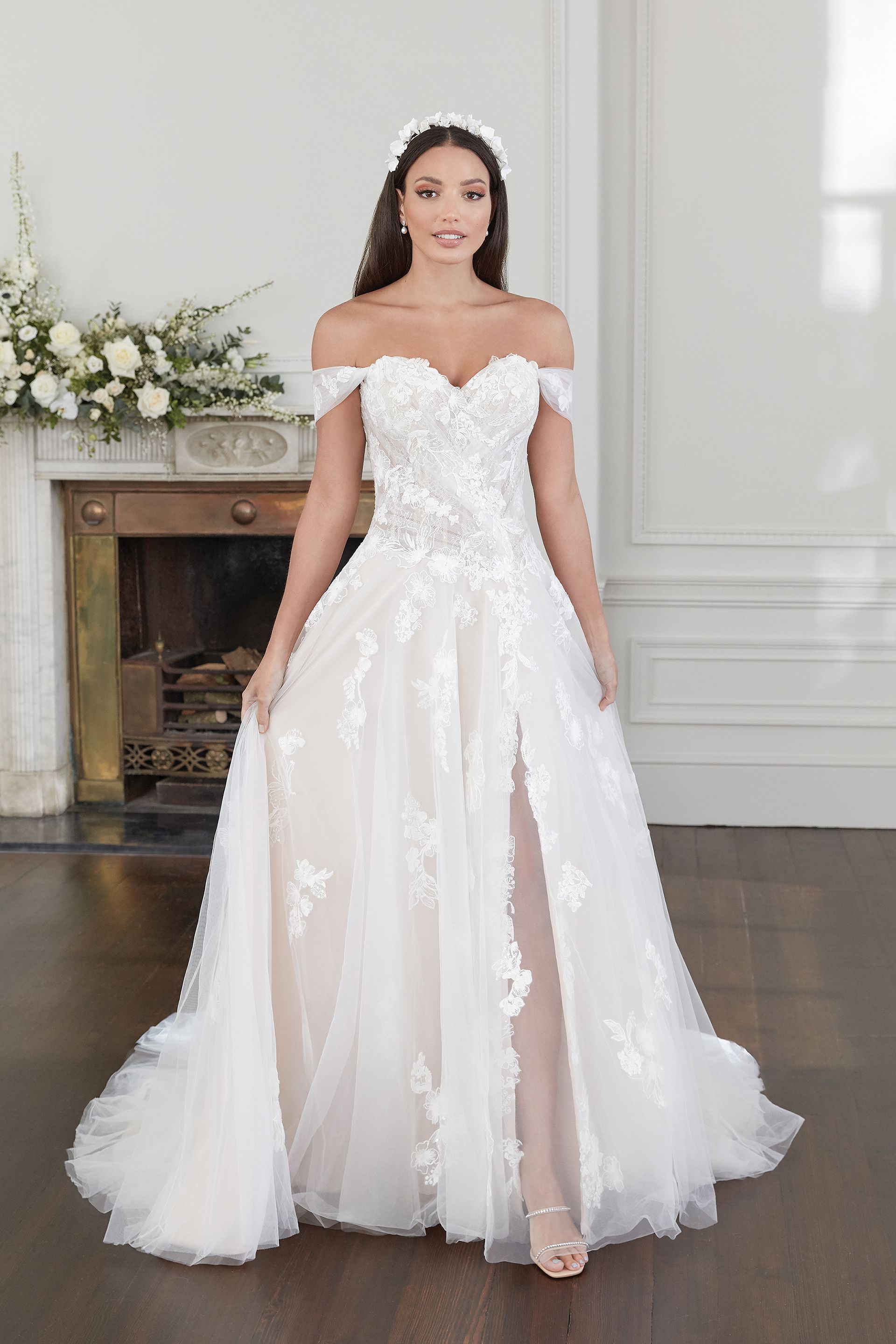 Eine Frau in einem weißen Hochzeitskleid steht vor einem Kamin.