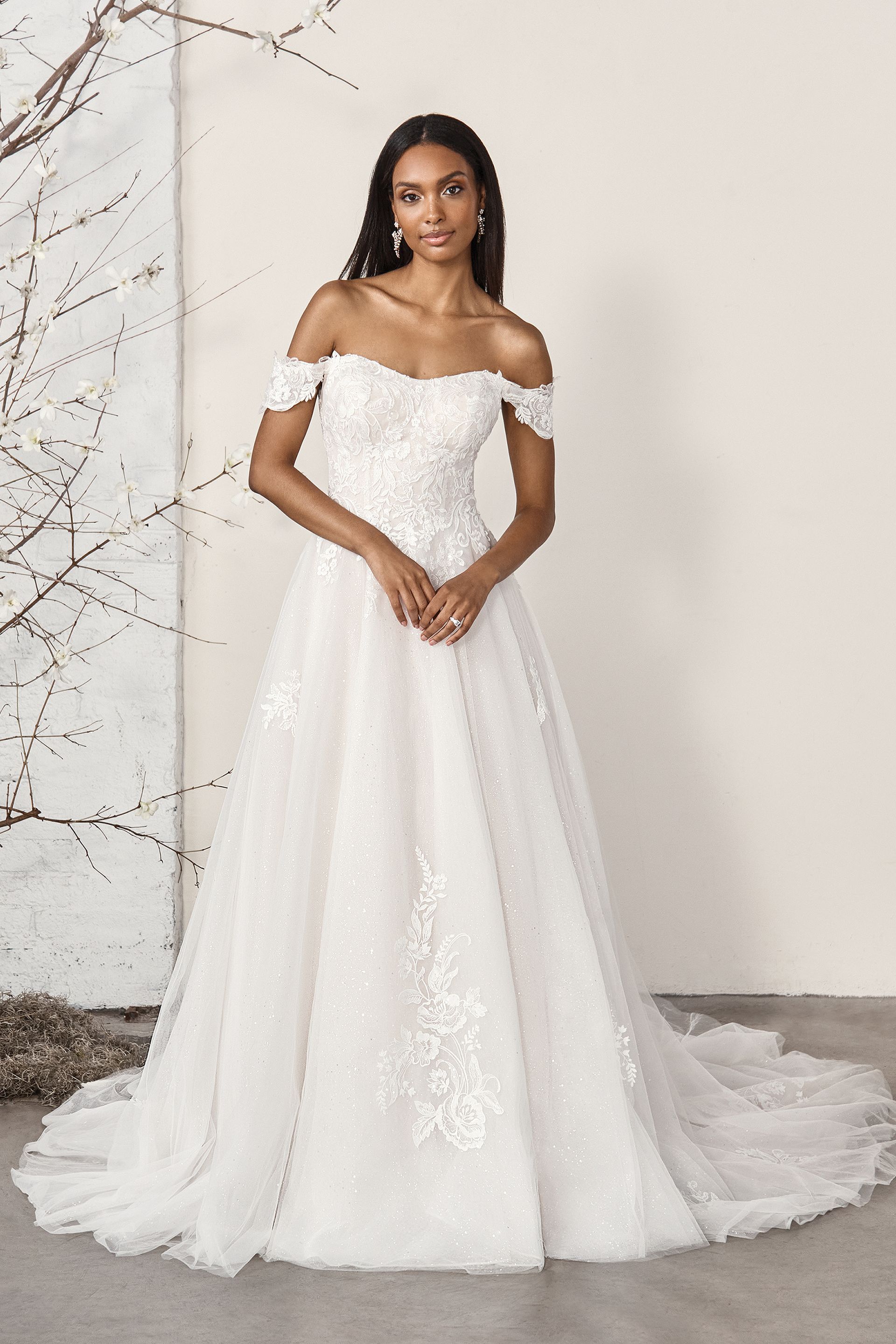 Eine Frau in einem weißen Brautkleid steht vor einer Wand.