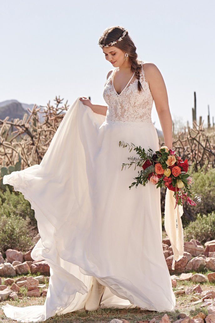 Die Braut trägt ein weißes Brautkleid und hält einen Blumenstrauß.