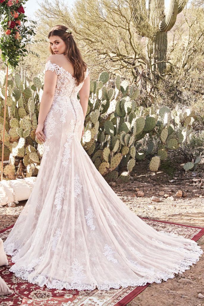 Eine Frau in einem Brautkleid steht vor einem Kaktus.