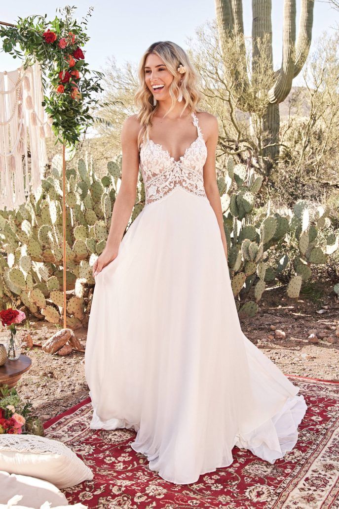 Eine Frau in einem weißen Hochzeitskleid steht vor einem Kaktus.