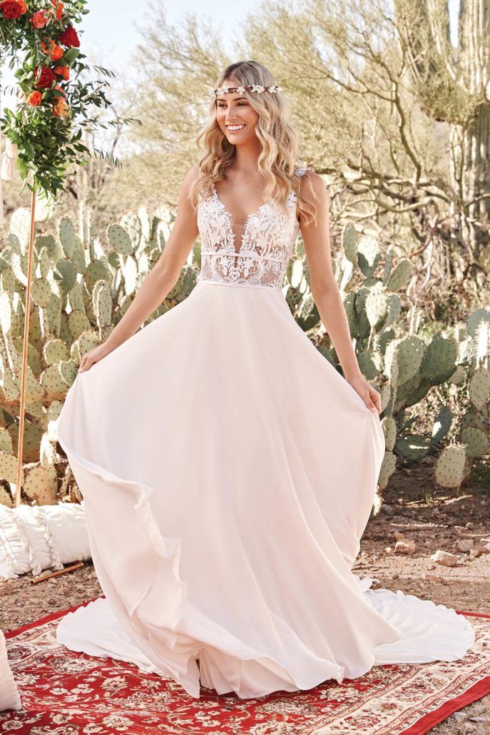 Eine Frau in einem Hochzeitskleid steht auf einem Teppich in der Wüste.