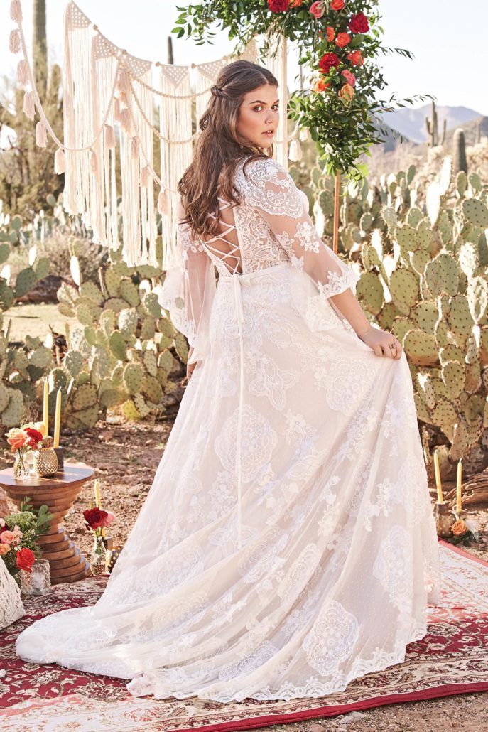 Eine Frau in einem Brautkleid steht vor einem Kaktus.