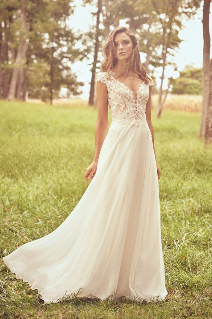Eine Frau in einem weißen Hochzeitskleid steht auf einem Feld.