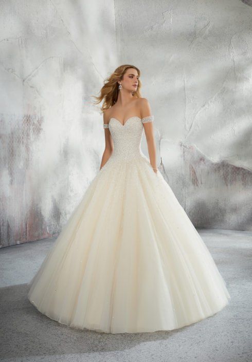 Eine Frau in einem weißen Ballkleid steht vor einer Wand.