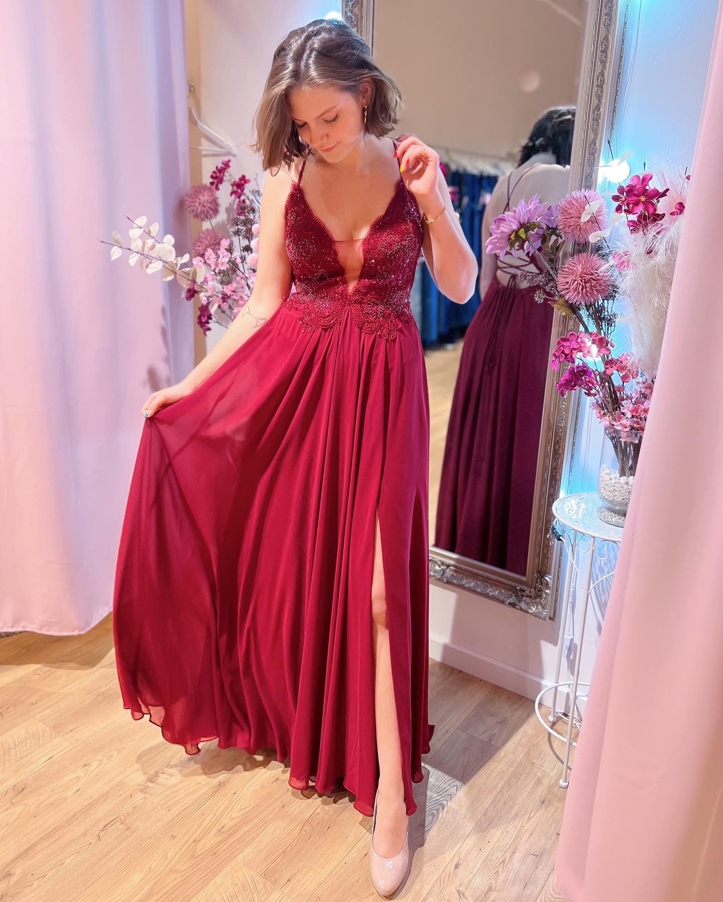 Eine Frau in einem roten Kleid steht vor einem Spiegel.