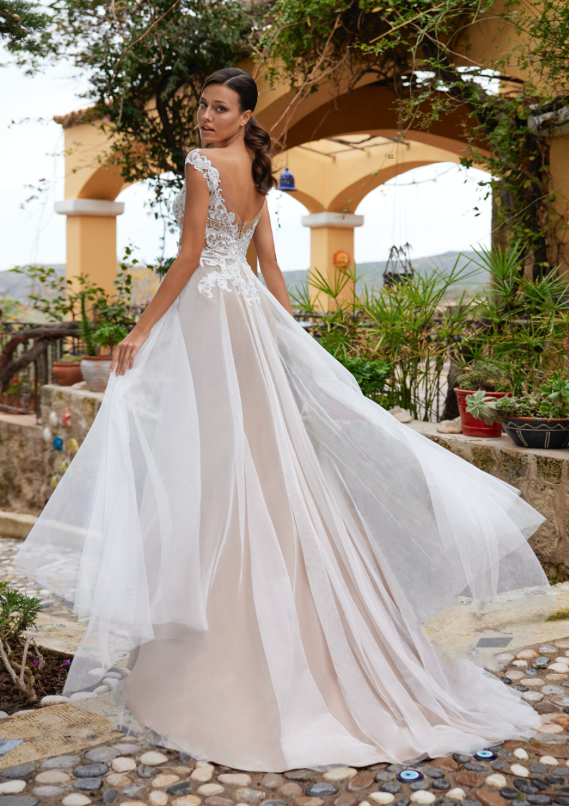Eine Frau in einem weißen Brautkleid steht vor einem Gebäude.