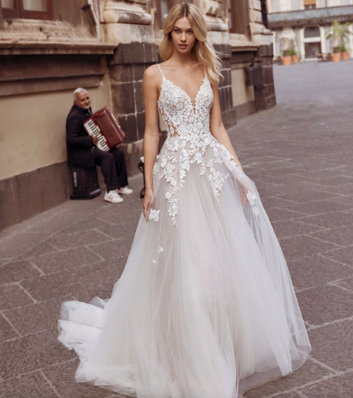 Eine Frau in einem weißen Hochzeitskleid geht die Straße entlang.