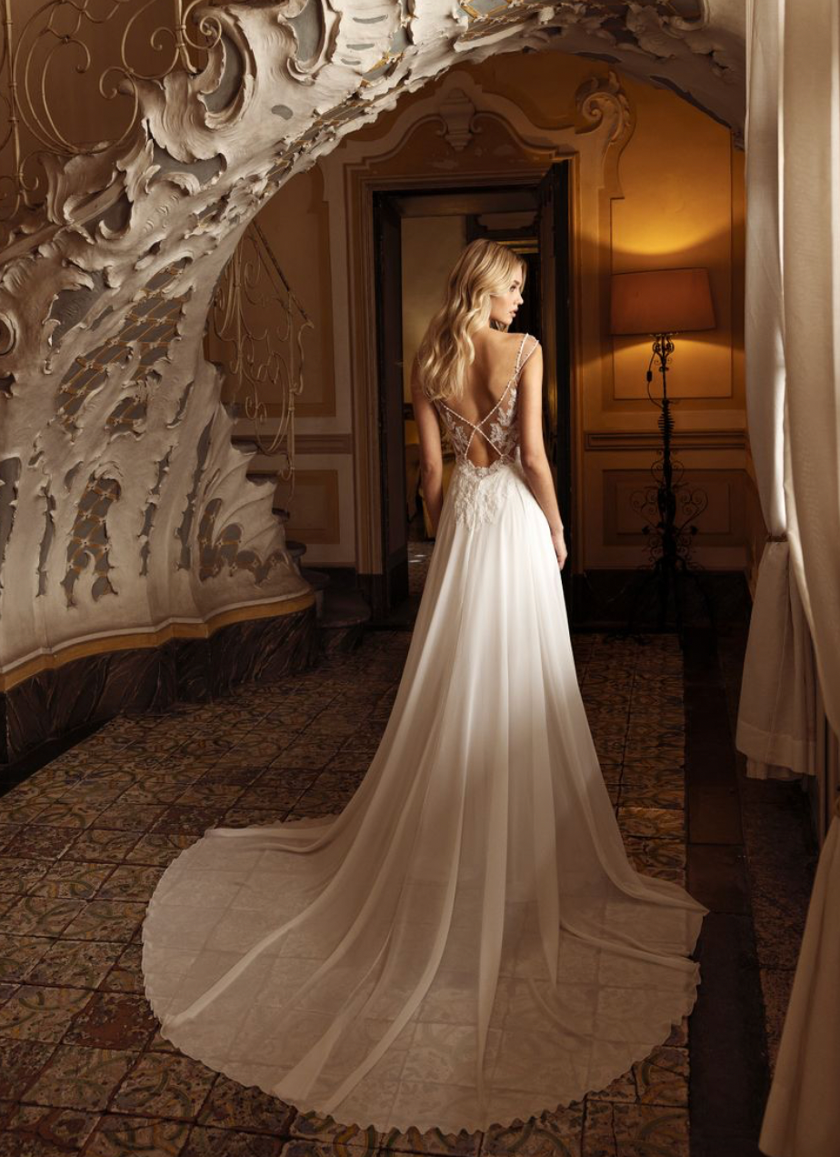 Eine Frau in einem Brautkleid steht in einem Raum neben einer Treppe.