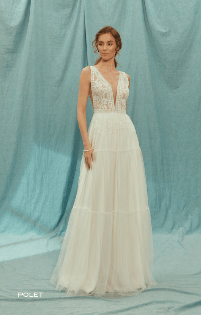Eine Frau in einem weißen Kleid steht vor einem blauen Vorhang.