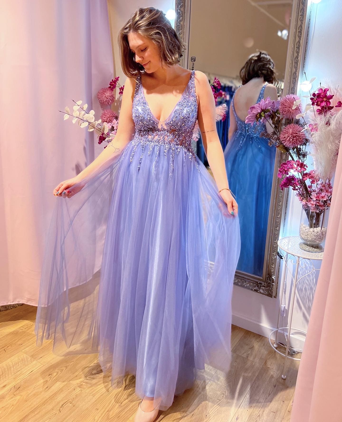 Eine Frau in einem lila Kleid steht vor einem Spiegel.