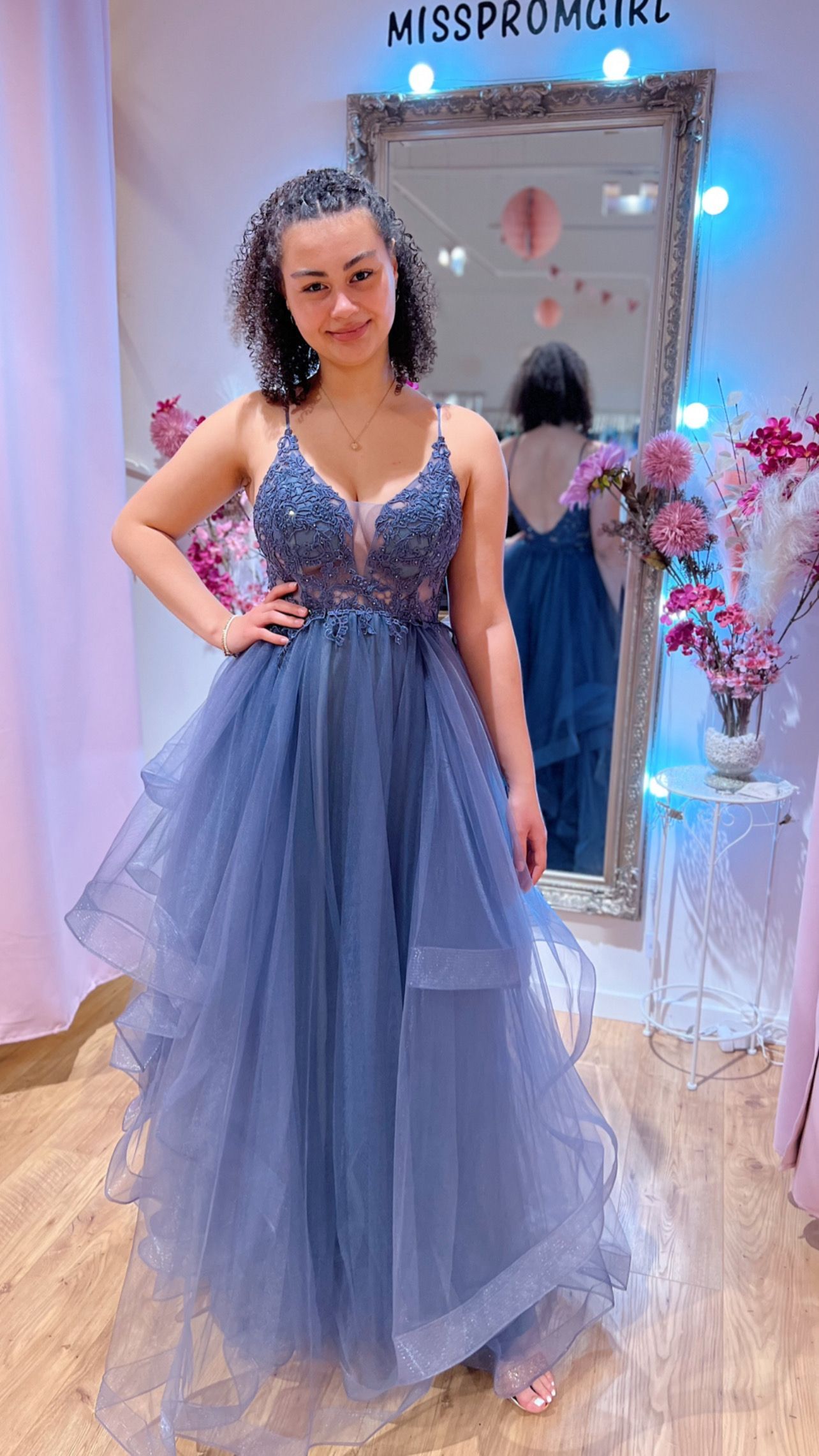Eine Frau in einem blauen Kleid steht vor einem Spiegel.
