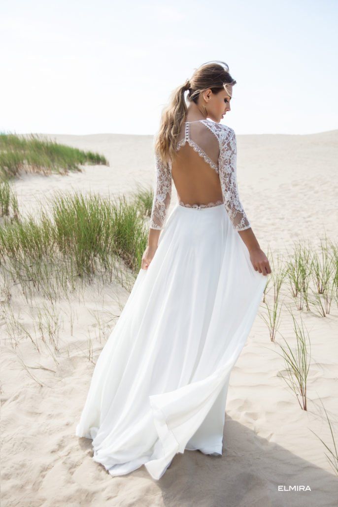 Eine Frau in einem weißen Hochzeitskleid steht an einem Sandstrand.